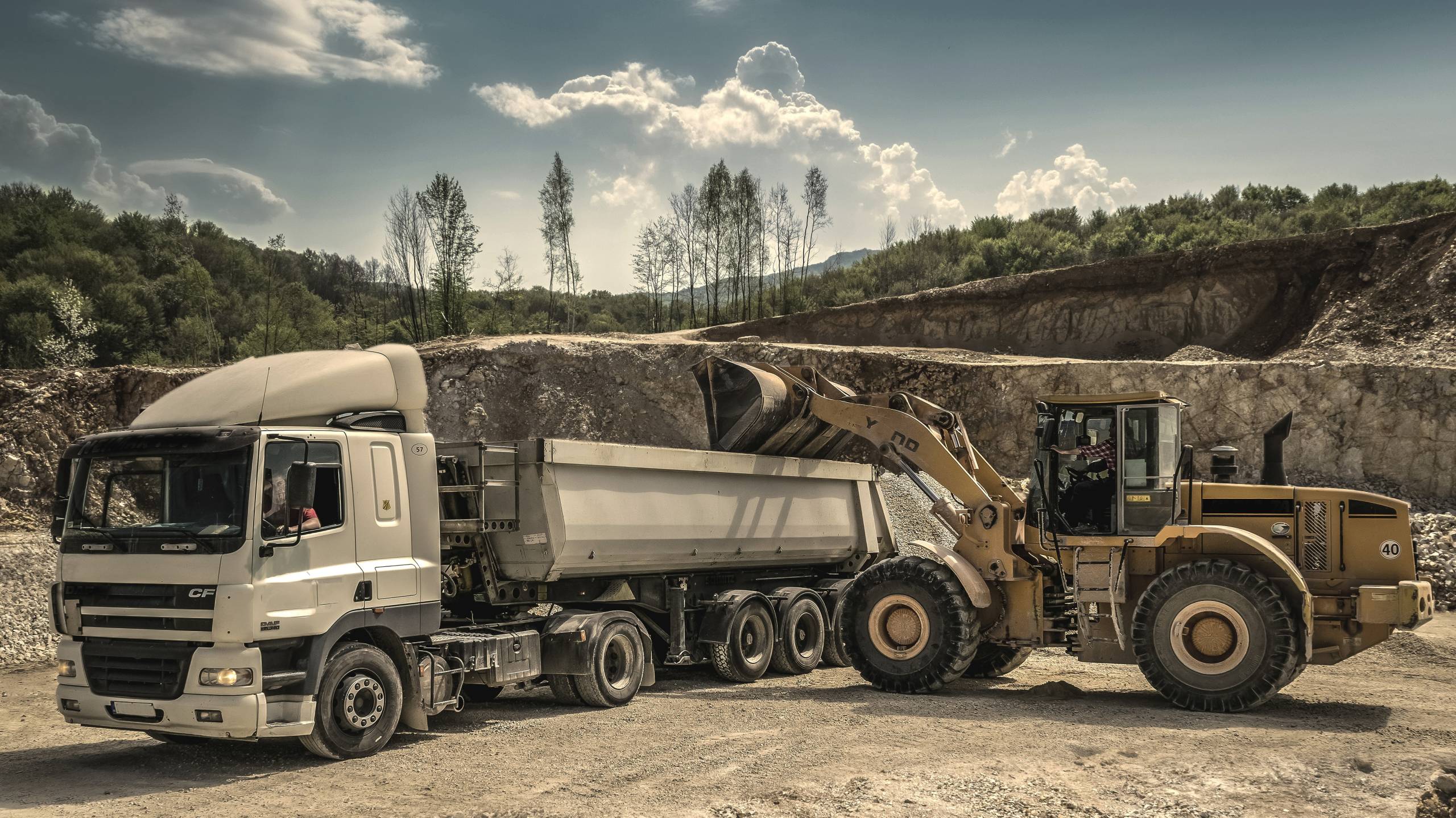 Front Load Loader Beside White Dump Truck